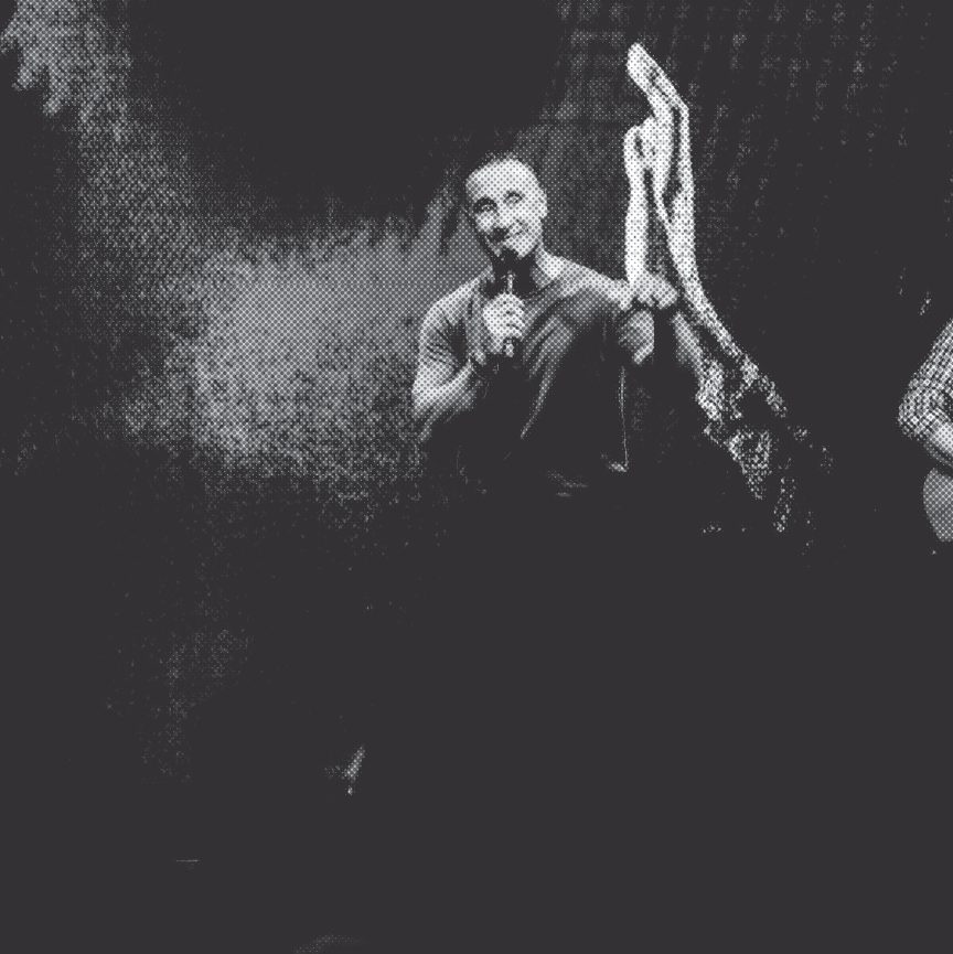 A pastor speaking with a microphone, hand raised